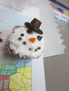 a cupcake decorated like a snowman with a top hat