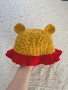 a crocheted hat with ears is being held by a person's hand