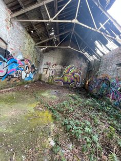 an abandoned building with graffiti on the walls and ceiling, covered in leaves and grass