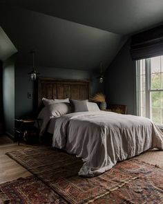 a large bed sitting in the middle of a bedroom next to a window and rug