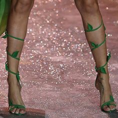 a woman's legs with green straps on the runway