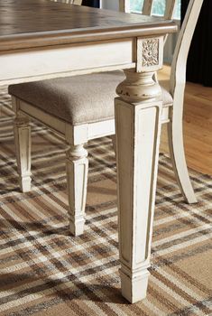 a dining room table with two chairs and a bench in front of it on a checkered area rug