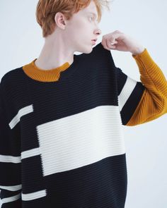 a young man with red hair wearing a black and white striped sweater looking off to the side