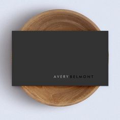 a black business card sitting on top of a wooden plate