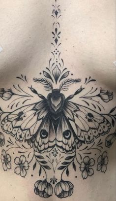 the back of a woman's chest with a butterfly and flowers tattoo on it