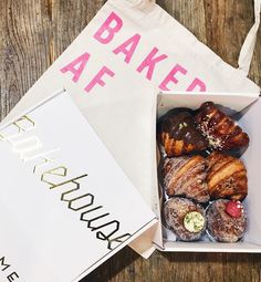 a box filled with pastries sitting on top of a table next to a bag