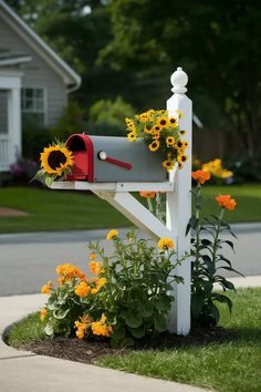 a mailbox with sunflowers in the flower bed