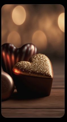 two heart shaped chocolates sitting next to each other on top of a wooden table