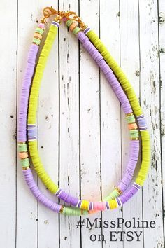 a multi - colored necklace is displayed on a white wooden surface