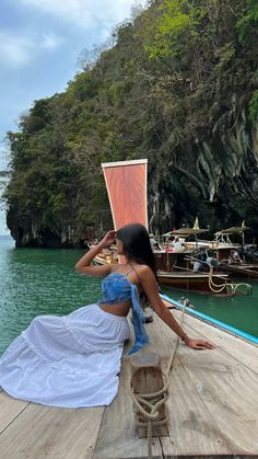 a woman sitting on top of a wooden pier