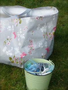 a green bucket with toothbrushes in it next to a white bag on the grass