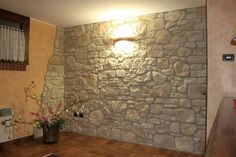 a stone wall in the corner of a room with wood flooring and potted plants