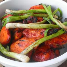 a white bowl filled with carrots and asparagus on top of a wooden table