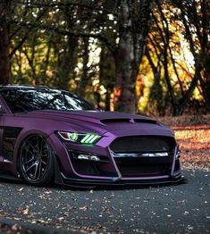 a purple sports car parked in front of some trees