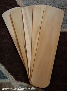 four wooden paddles laying on top of each other next to a carpeted area