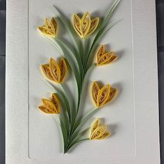 some yellow flowers are sitting in a white frame on a table and it looks like they have been cut out of paper