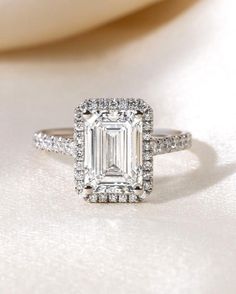 an emerald - cut diamond ring with pave diamonds surrounding it