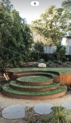 a circular garden design in the middle of a yard with steps leading up to it