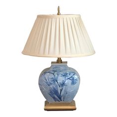 a blue and white vase with flowers on it next to a lampshade that is turned on