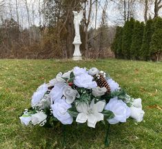 a bouquet of white flowers sitting on top of a lush green field next to a statue