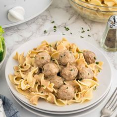 a white plate topped with meatballs and pasta next to broccoli on a table