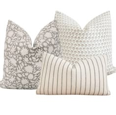 three pillows with different patterns on them, one in grey and the other in white