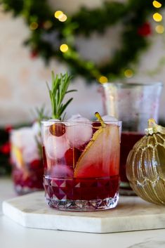 two glasses filled with red liquid and garnished with rosemary