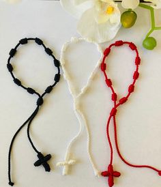 three different types of bracelets with flowers on the table next to them and one is black, white, and red