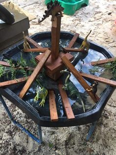 an upside down bird bath with plants growing out of the water and wooden sticks sticking out of it's sides