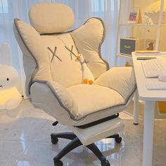 an office chair with a cat pillow on it in front of a desk and computer