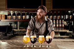 a man is holding three glasses of beer