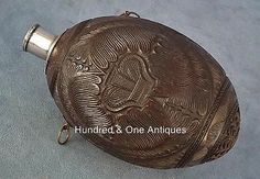 an antique brass flask with ornate designs on the outside and inside, sitting on a gray surface