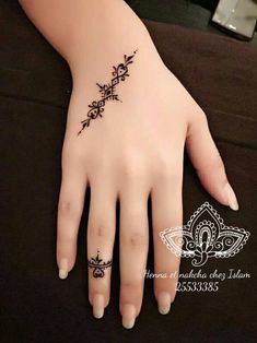 a woman's hand with a black henna tattoo on her left wrist and finger