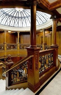 an ornate staircase in a building with glass dome above the railing and wood paneling