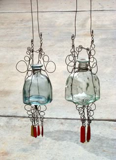 two glass vases hanging from hooks on concrete