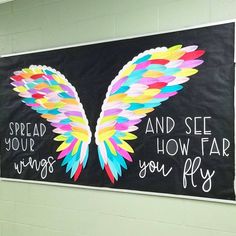 a bulletin board with colorful wings painted on it and the words spread your wings, how far do you fly?