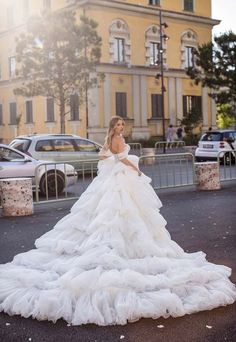 a woman in a wedding dress standing on the street