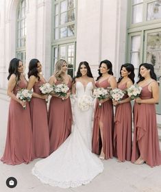 a group of women standing next to each other in front of a building with bouquets