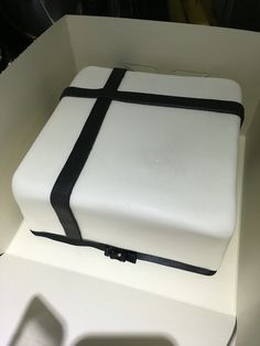 a white cake with black trim in a box