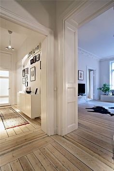 an open door leading to a living room with pictures on the wall and hardwood floors