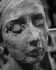 black and white photograph of a woman's face made out of clay with paint on it