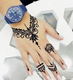 a woman's hand with henna tattoos and a watch on her left wrist