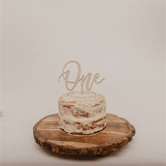 a cake sitting on top of a wooden plate with the word one written on it