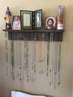 a shelf with rosarys and pictures on top of it next to a toilet in a bathroom