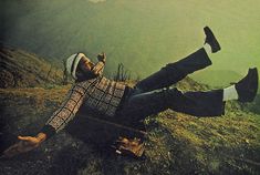 a man laying on the ground with his feet up in the air and wearing a hat