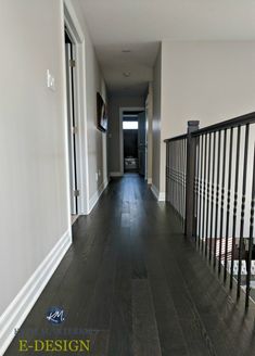 an empty hallway with wood floors and black railings