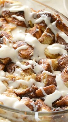 a glass dish filled with cinnamon rolls covered in white icing and drizzle