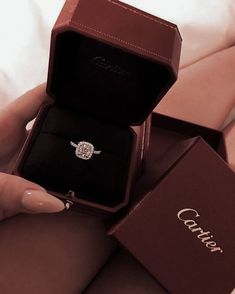 a woman is holding an engagement ring in her red box with the word couture written on it