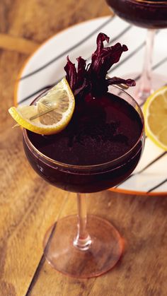 a glass filled with purple liquid and garnished with lemon wedges on a wooden table