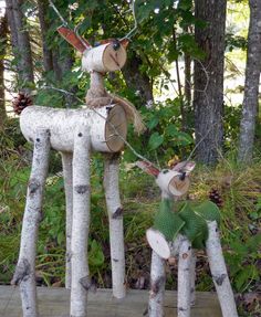 two deer made out of birch trees with green scarfs on their heads and legs